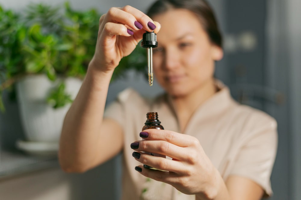 Personne tenant un flacon d’huile de CBD avec une pipette, prête à administrer quelques gouttes.