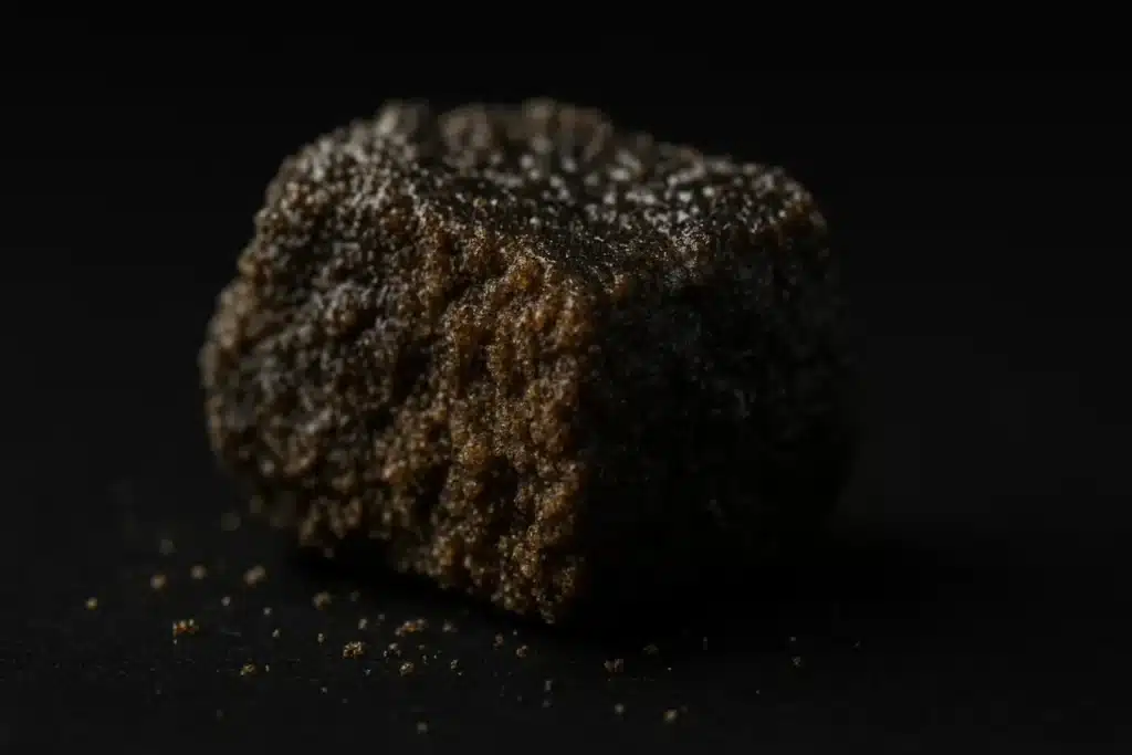 Gros plan d’un morceau de résine CBD naturelle BUDDY BOO, sombre et riche en trichomes