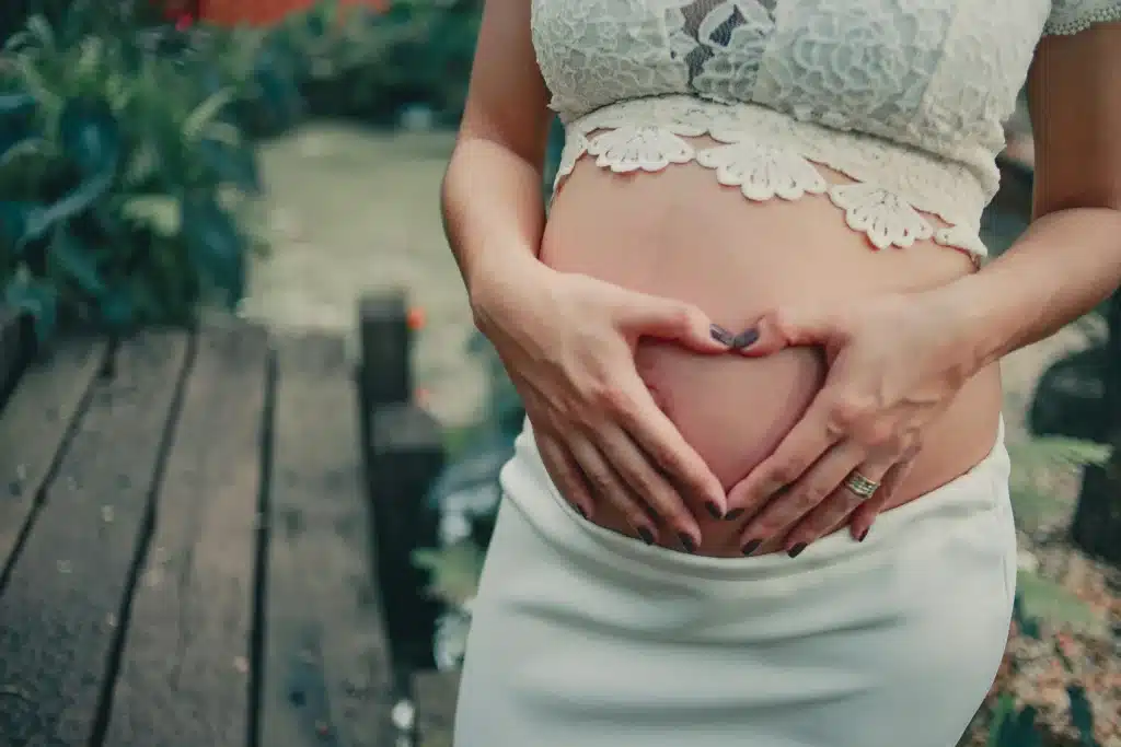 Femme enceinte formant un cœur sur son ventre, illustrant la tendresse et les précautions autour du CBD grossesse avec BUDDY BOO.