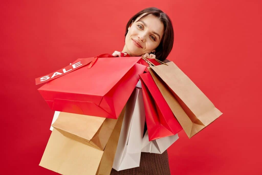 Femme souriante portant plusieurs sacs de shopping pendant les soldes de CBD prix bas chez BUDDY BOO