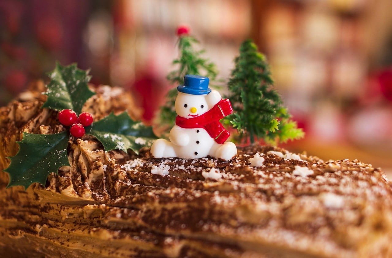 Bûche de Noël décorée avec un bonhomme de neige et du houx, illustrant la recette bûche Noël CBD proposée par BUDDY BOO.